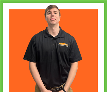 SERVPRO employee in front of orange wall