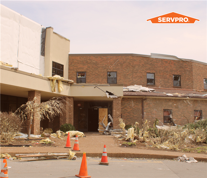 commercial property, torn apart by a storm, orange/brown brick building medium shot, servpro logo in upper right